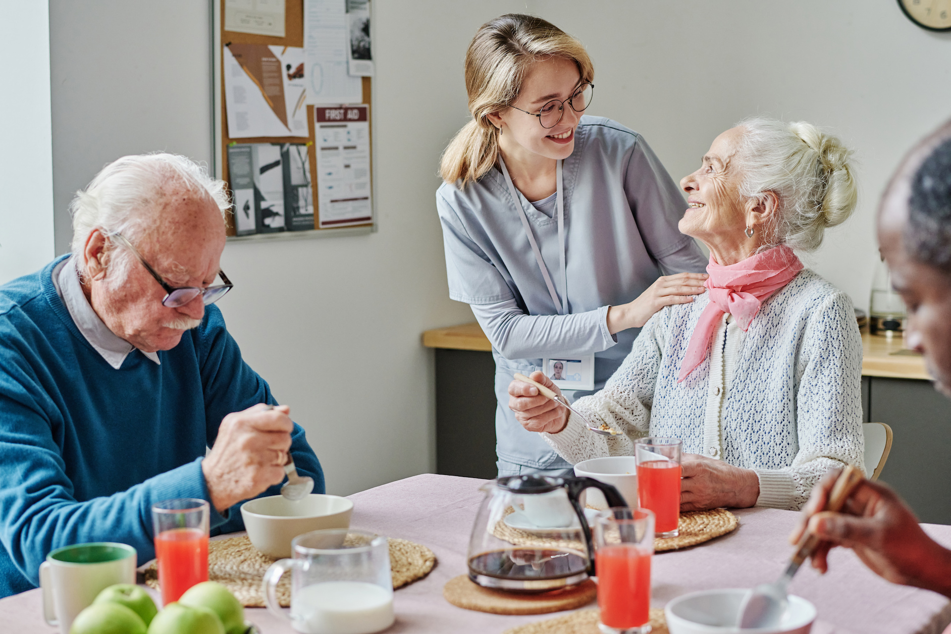 Caregiver helping senior people during lunch